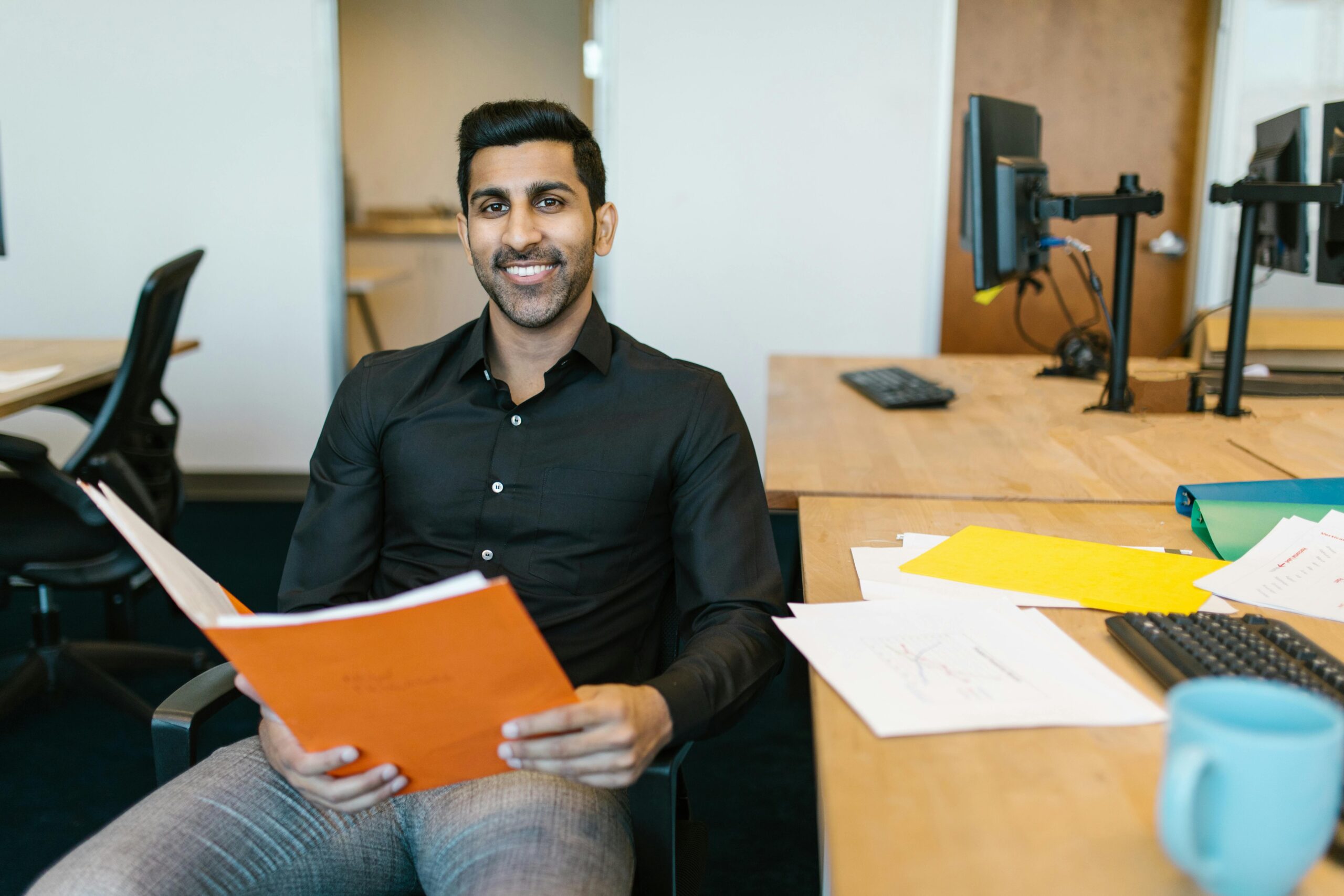 Man in black long sleeve shirt holding orange folder