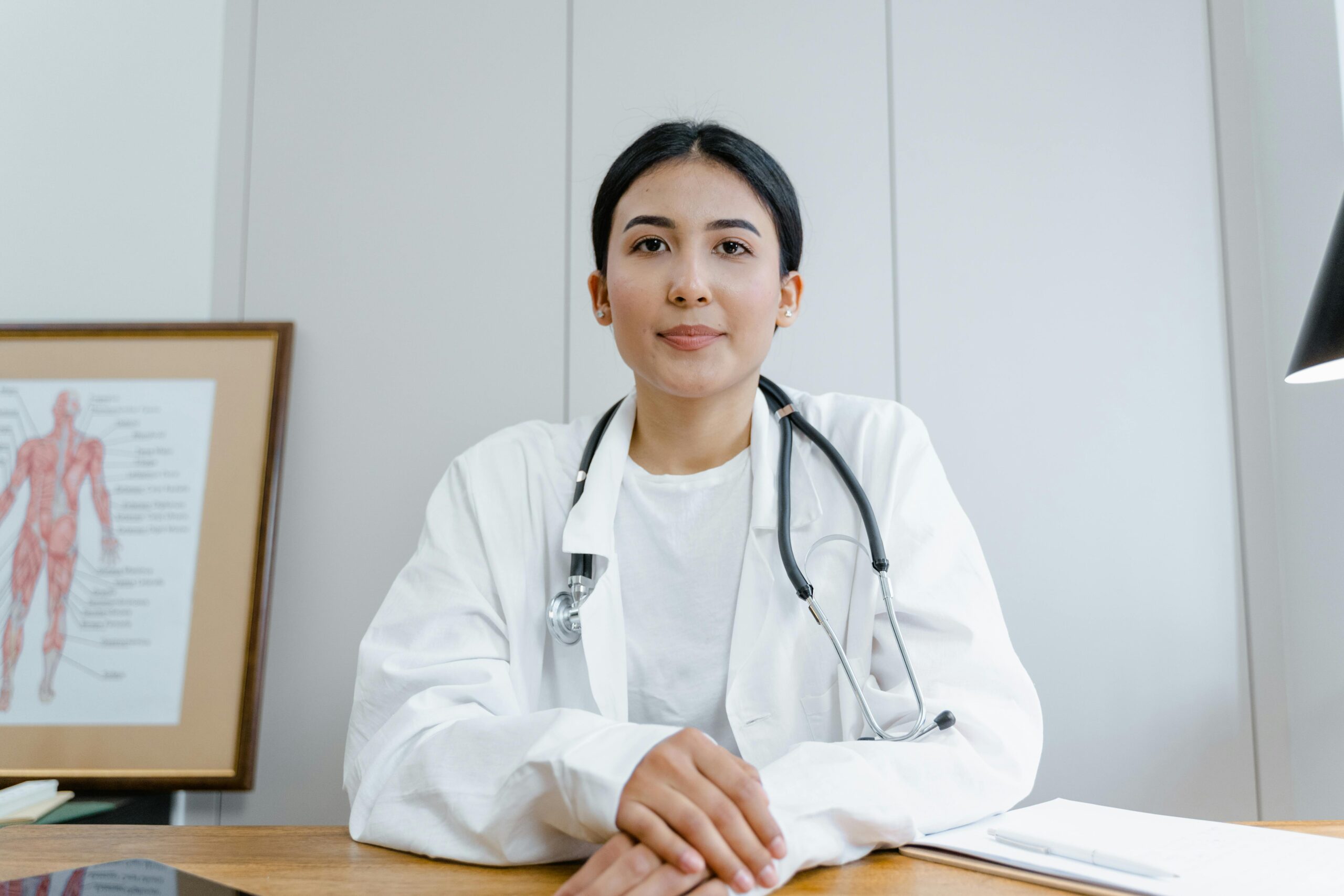 Woman in white scrub suit wearing black stethoscope