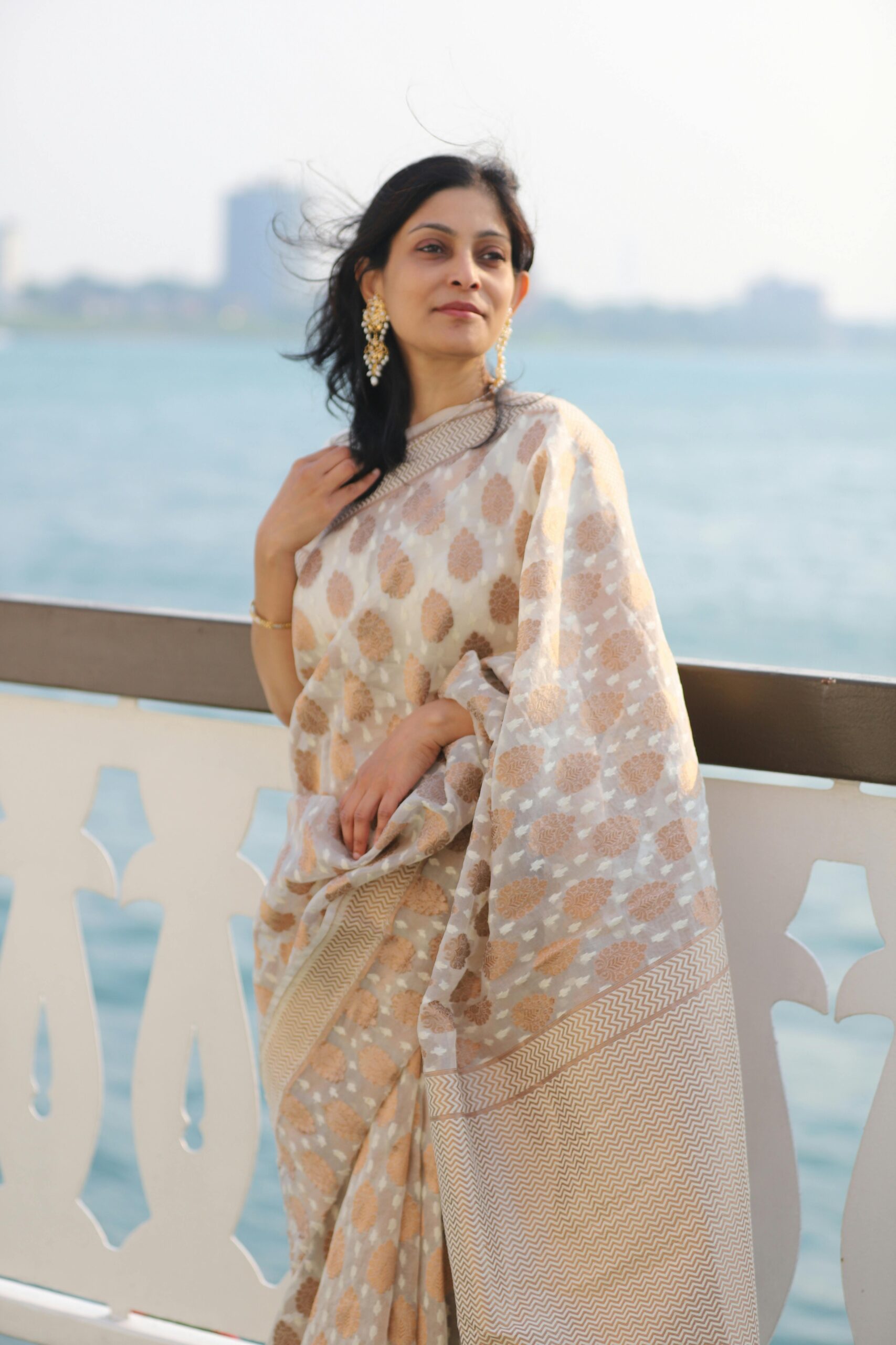 Young woman leaning against a railing with sea in the background